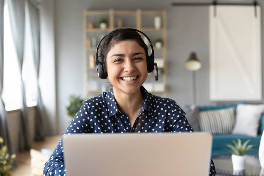 femme souriante utilisant Teams sur son ordinateur portable