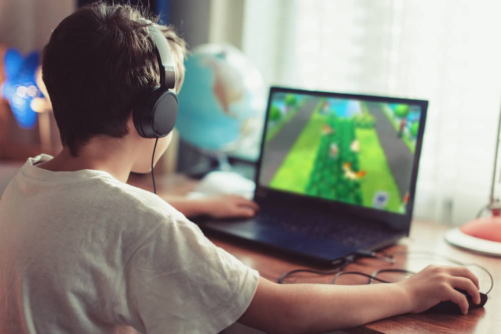 adolescent jouant à Minecraft sur un ordinateur portable